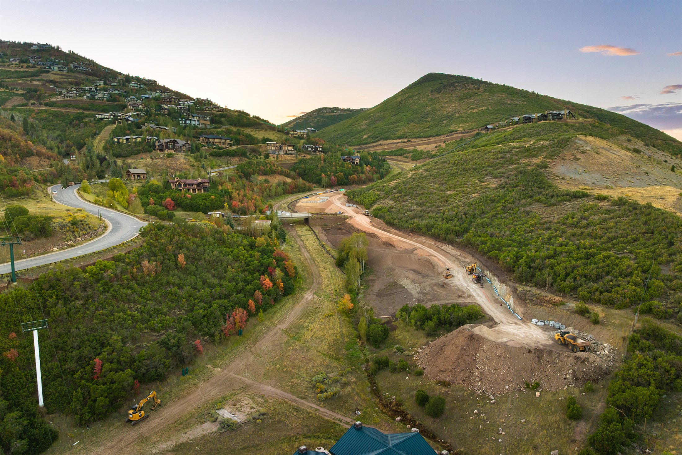 Excavators and a haul truck working along a utility trench on the east end of the site